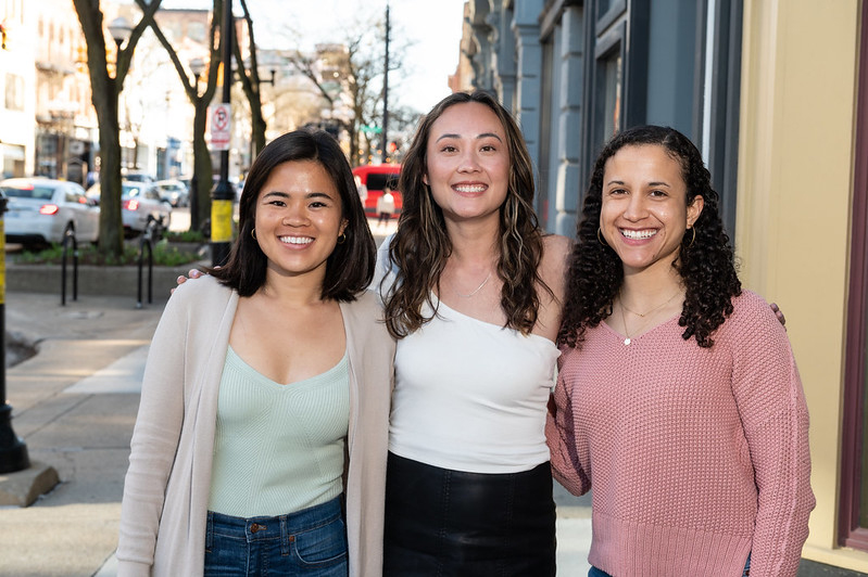 Three women of various ethnicities from team Community Collective, posed outside.