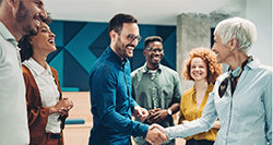 Man shaking hands with a woman in front of a group