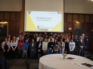 Student grantees pose in a group photo in front of presentation slides