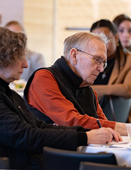 Older man next to older woman at table taking notes