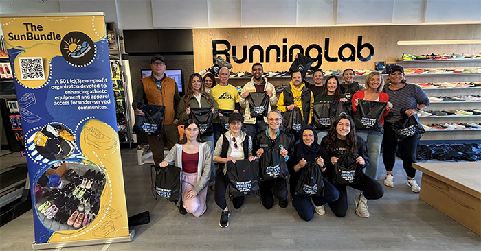 Group of people in front of Running Lab sign and next to SunBundle sign.