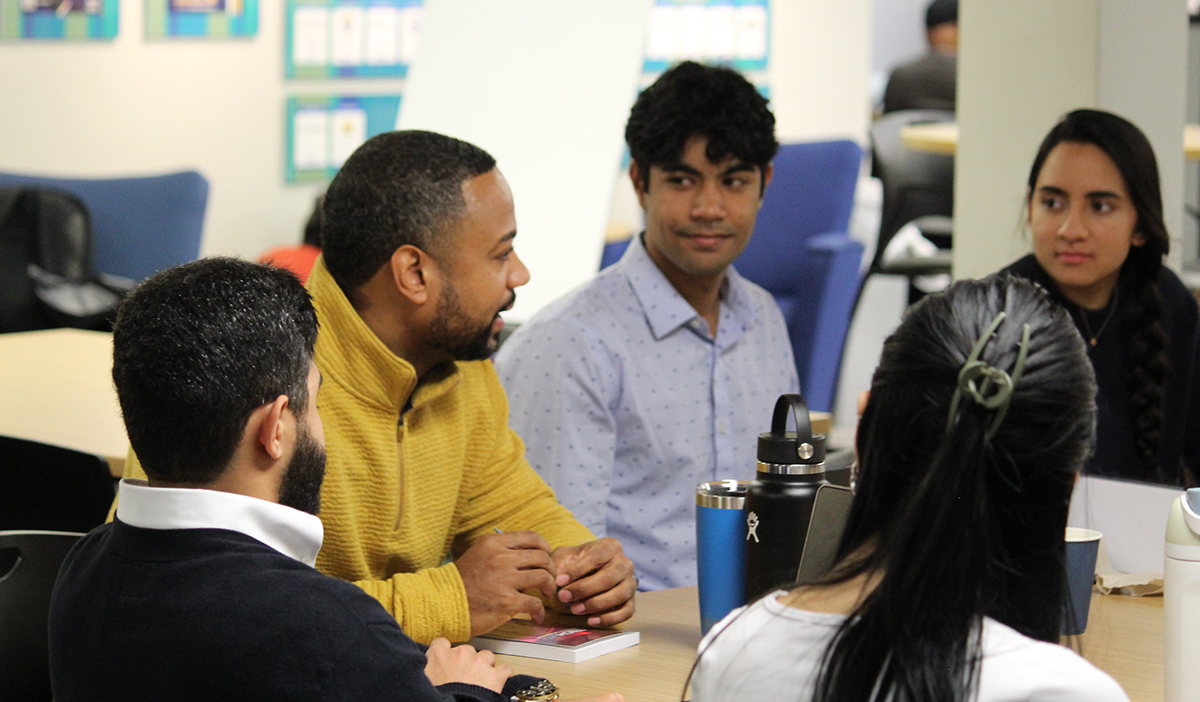 Loren Townes speaking to two male and two female students at a table with waterbottles on it