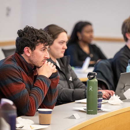 Young man and young woman looking offscreen in a classroom with a young black woman in the background