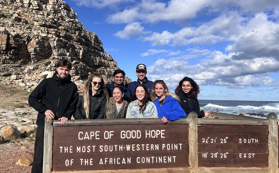 Diverse group of students standing at a sign for the Cape of Good Hope in Africa