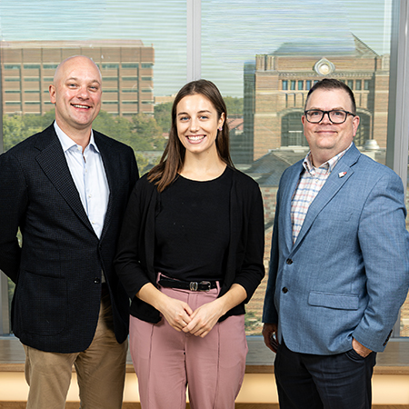 Young woman student standing between two older men professionals