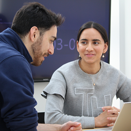 Latin American woman in the Impact Studio, looking at Latin American man and smiling