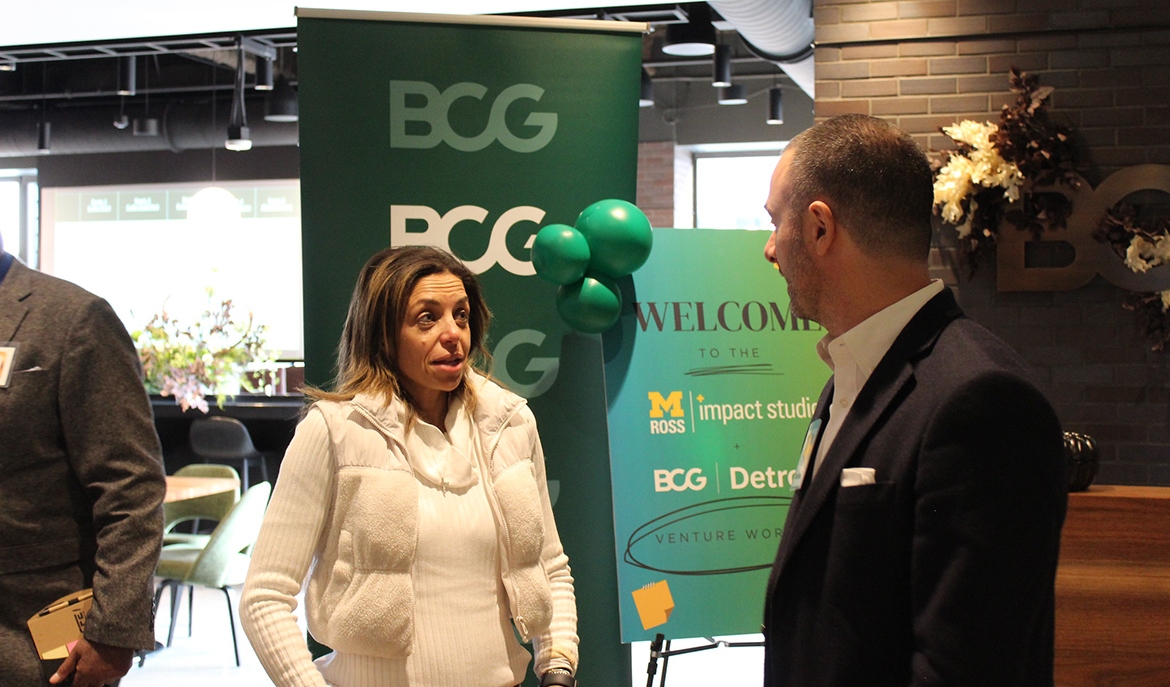 Woman speaking with man in front of signage for BCG Detroit