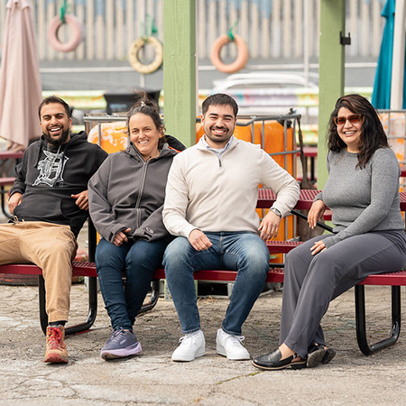 Diverse group of two men and two women sitting on a bench outdoors at a Detroit urban garden