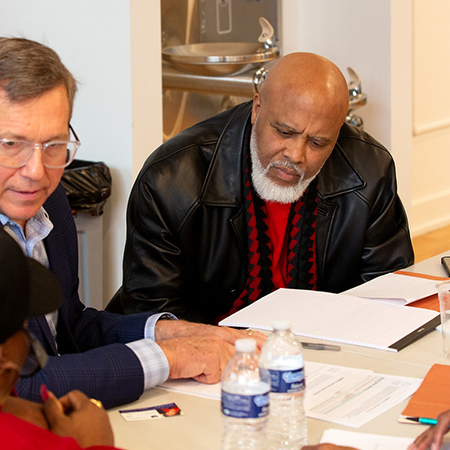 White man and black man sitting together at a table with papers