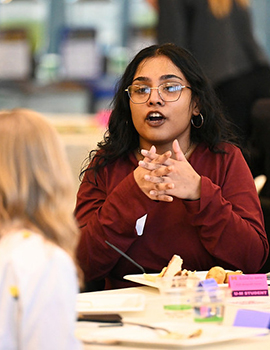 Young woman of color explaining something to a blond woman sitting together at a table