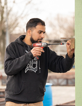 Young male student screwing board into pole wearing a Detroit Tigers sweatshirt.
