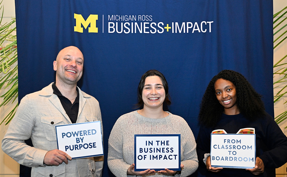 White bald man, white young woman and black young woman holding signs saying 