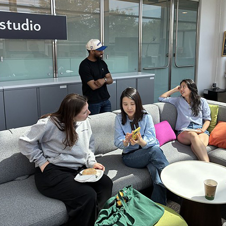 Four diverse students talking casually in the Impact Studio
