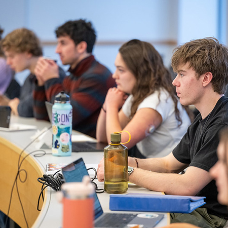3 young men and 1 woman listening in a classroom