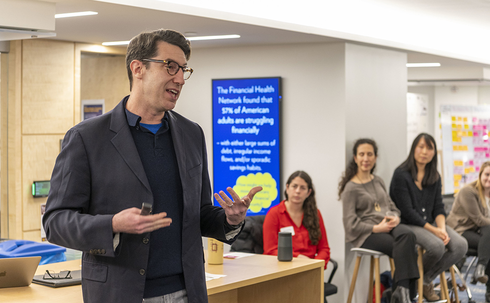 White man presenting in front of group in the Impact Studio