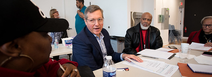White man talking with black man at a long office table.