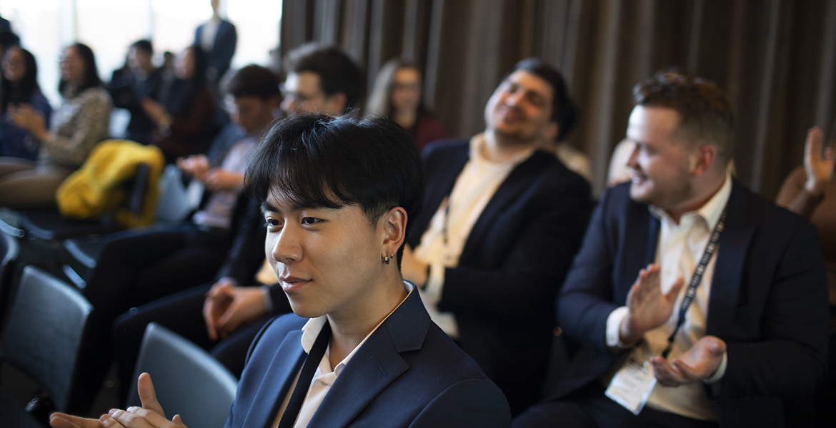 Asian man at cocurricular event, with others in the background of the audience
