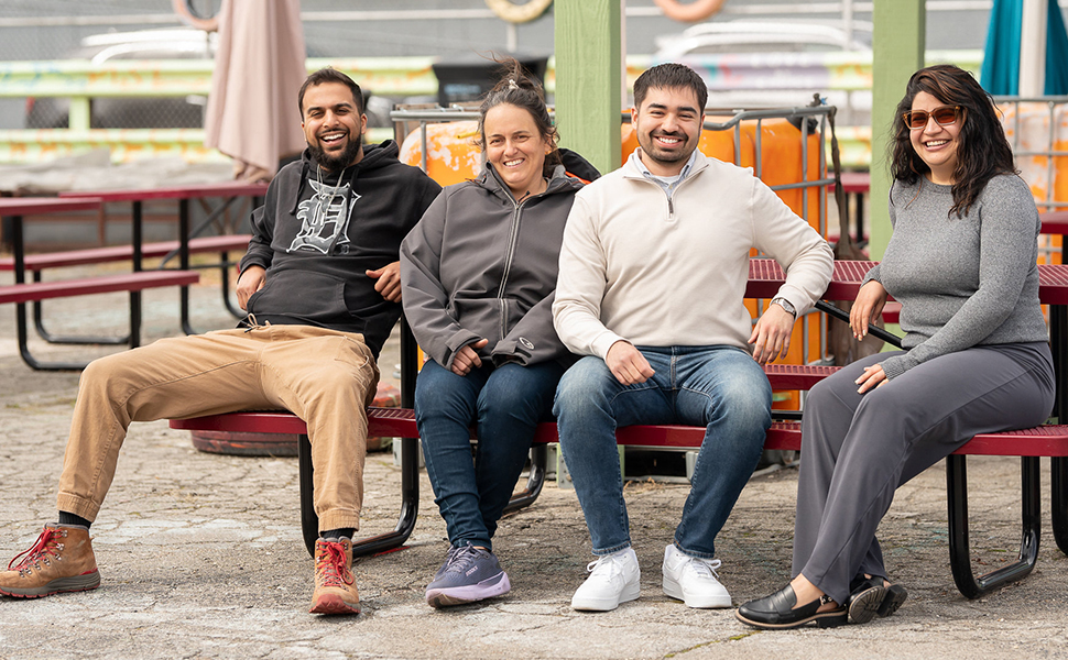 Diverse group of men and women of different ethnic backgrounds sitting at a picnic table at Urban Gardens in Detroit