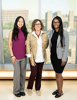Asian woman, Black women and white woman posed in front of a window at a Board Fellows event