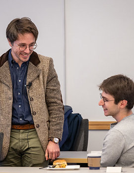 Xavier Blot standing and smiling over a young male student