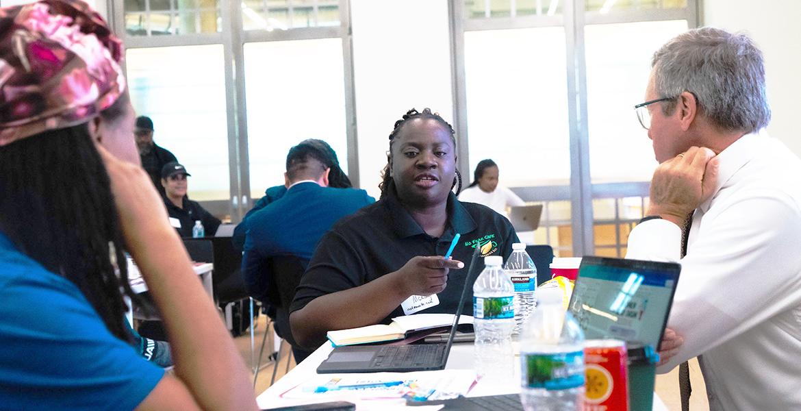 Black business owner at table explaining business issues to man and woman who are listening raptly