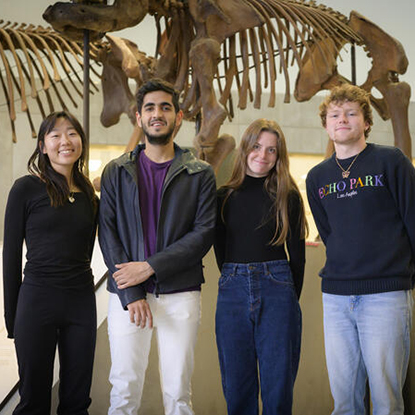 Two men and two woman from UM School of Information in front of a dinosaur skeleton