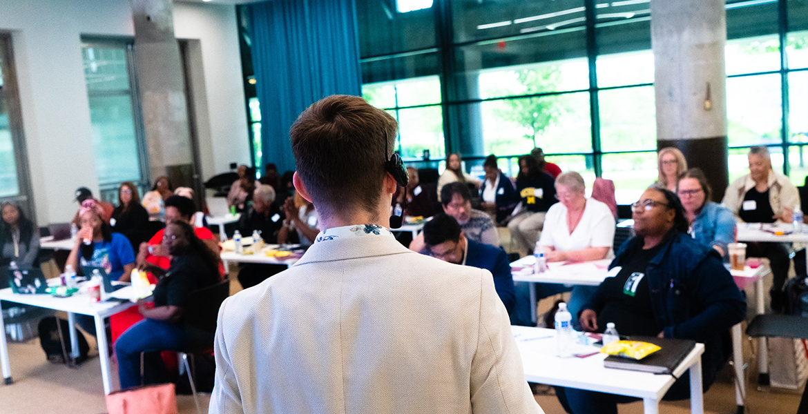 Student in a suit facing away from the camera, presenting to a group in Detroit