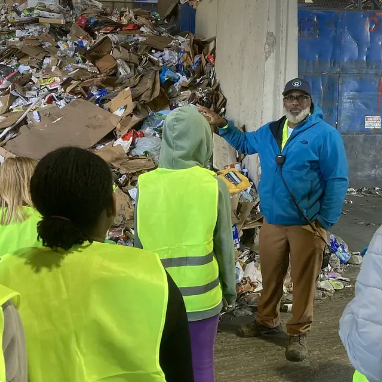 Individuals gathered at a recycling facility for a tour