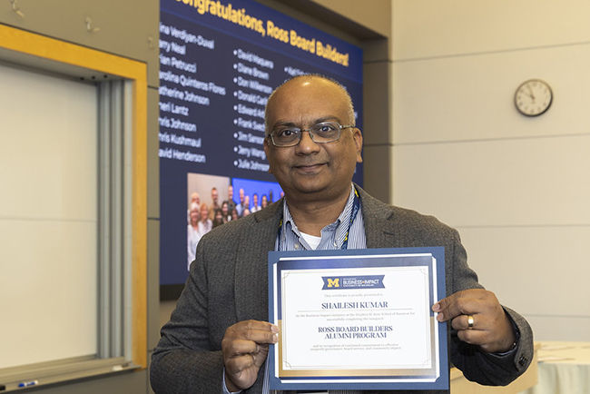 Shailesh Kumar holding up certificate of completion at Ross Board Builders event.